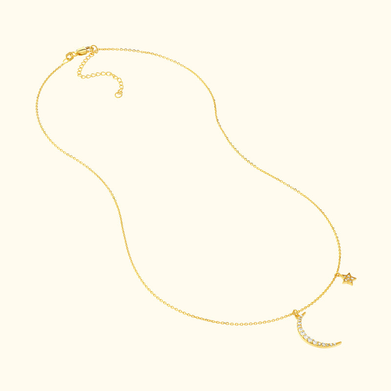 Delicate gold necklace featuring a crescent moon and star charm with sparkling accents.