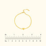 Gold bracelet with a heart charm, featuring a chain link design.