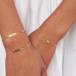 Two gold bracelets on a person's wrists, one engraved with "MOM" and the other with "LOVE."