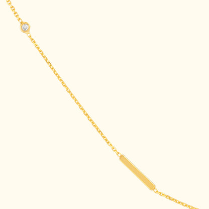 Delicate gold necklace featuring a bar pendant and a small diamond charm.