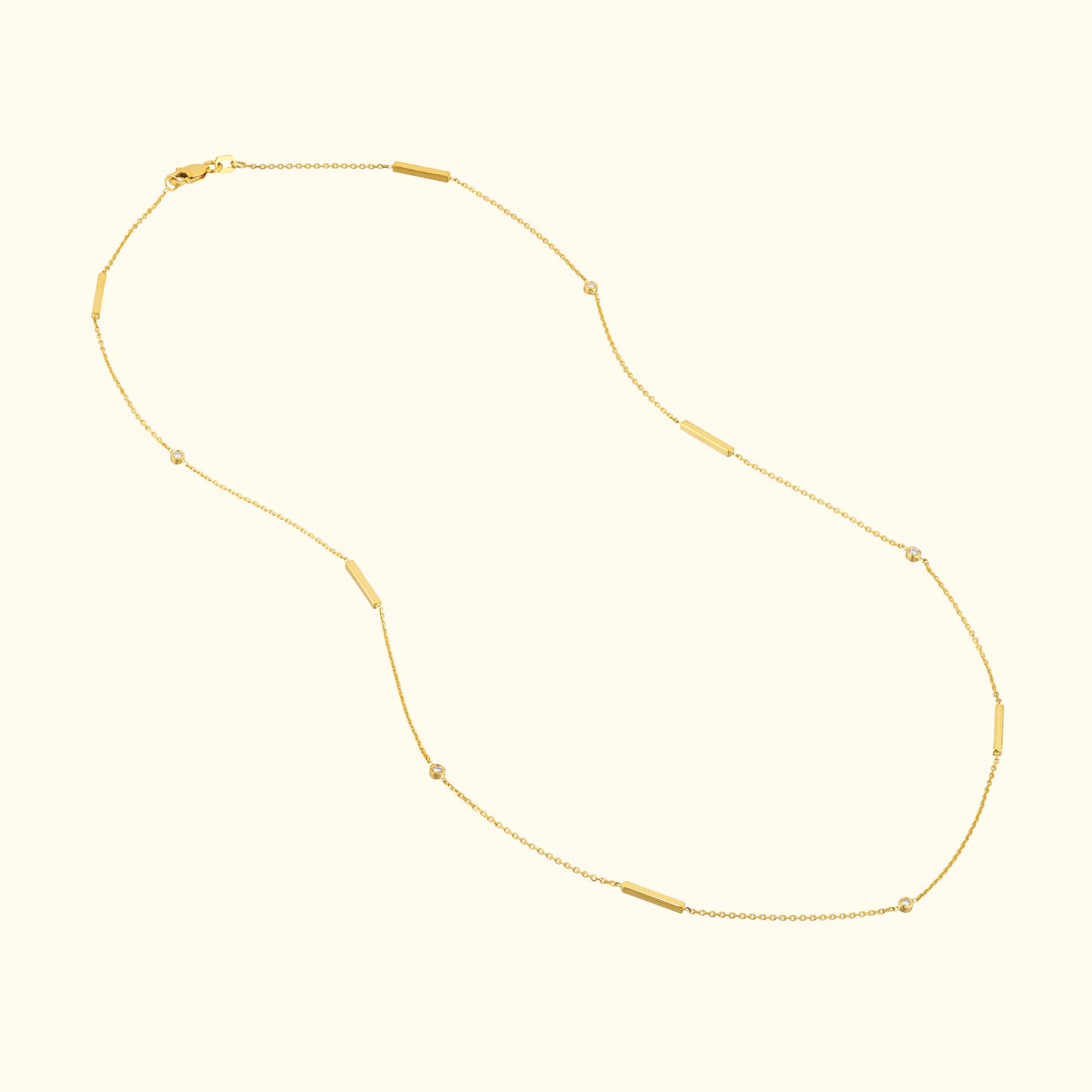 Delicate gold necklace with elongated and round beads, set against a light background.