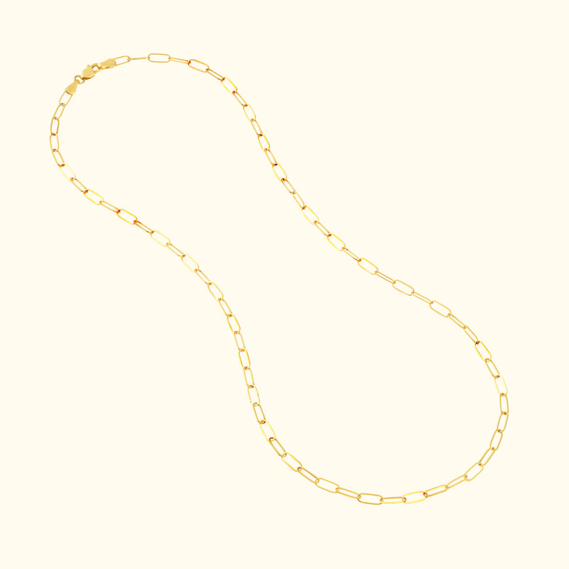 Gold chain necklace with elongated, linked design on a light background.