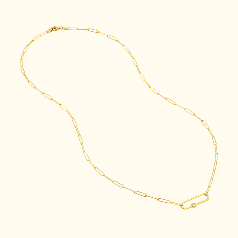 Delicate gold chain necklace with a central oval link and a small round bead.