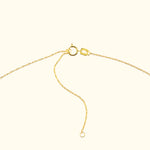 Golden necklace chain clasp with a delicate chain, resting on a light background.