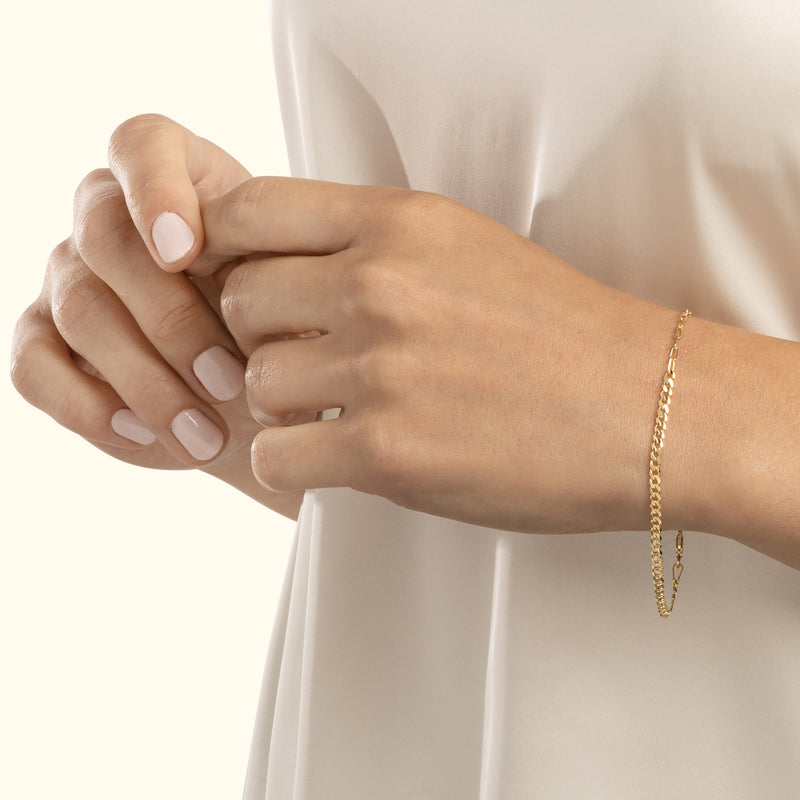 Delicate gold chain bracelet worn on a hand with neatly manicured nails.