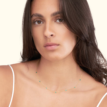 Delicate gold necklace with small turquoise stones worn by a model.