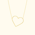 Gold heart-shaped pendant necklace on a delicate chain against a light background.