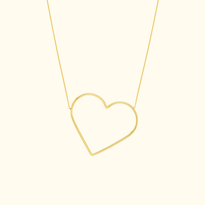 Gold heart-shaped pendant necklace on a delicate chain against a light background.