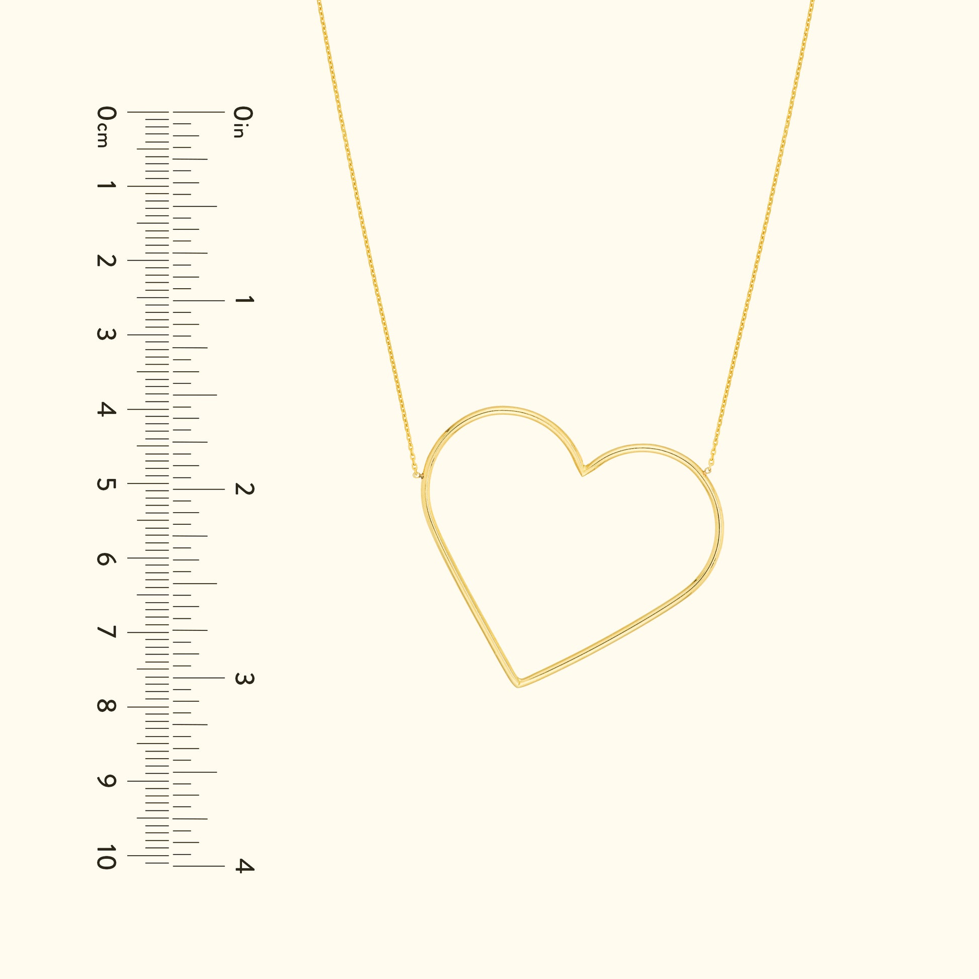 Gold heart-shaped necklace with a delicate chain, shown next to a ruler for scale.