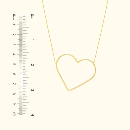 Gold heart-shaped necklace with a delicate chain, shown next to a ruler for scale.