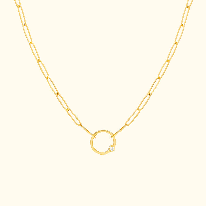 Gold chain necklace featuring a circular pendant with a small diamond.