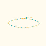 Gold chain bracelet adorned with small turquoise beads.