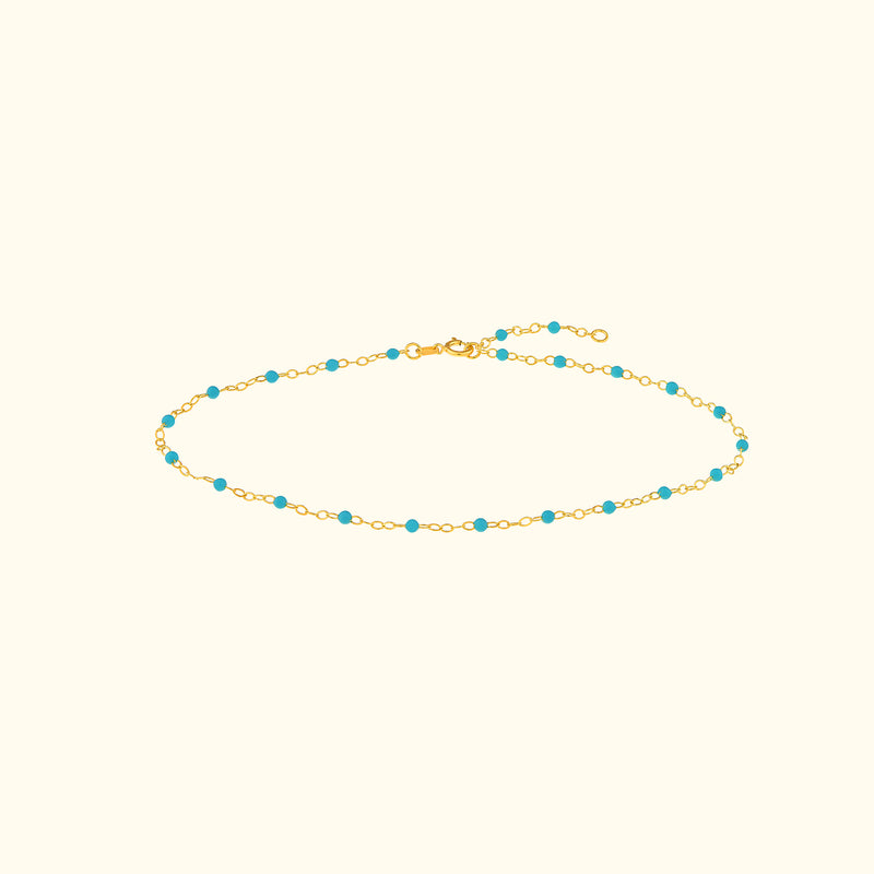 Gold chain bracelet adorned with small turquoise beads.