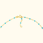 Gold chain necklace with turquoise beads and a clasp.