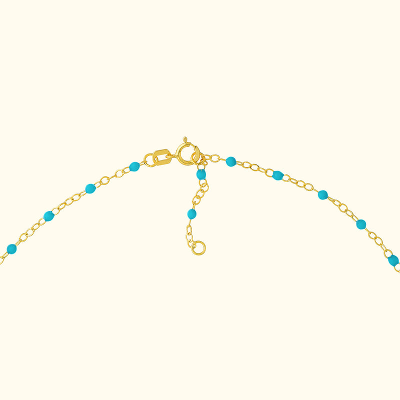 Gold chain necklace with turquoise beads and a clasp.