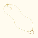 Gold heart-shaped necklace on a delicate chain against a light background.