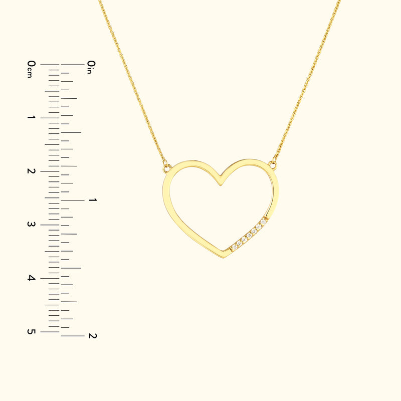 Gold heart-shaped necklace with small diamonds, positioned against a beige background.