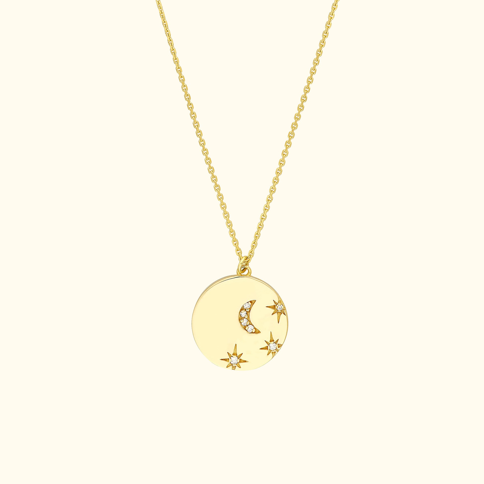 Gold pendant necklace with moon and star designs, accented with small gemstones.