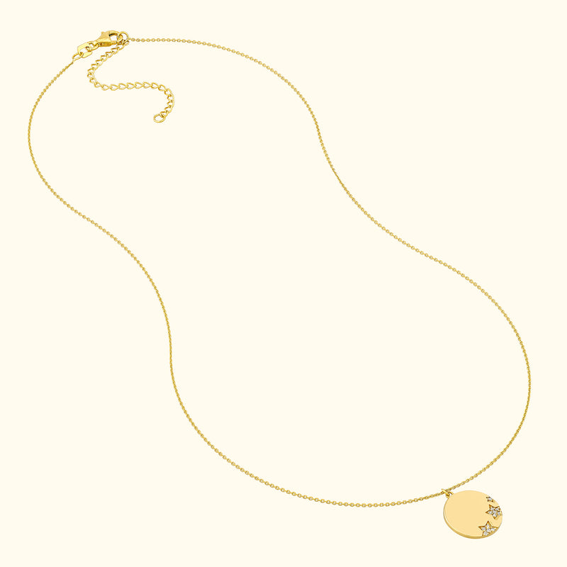 Delicate gold necklace featuring a round pendant with star motifs.