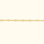 Gold chain bracelet with diamond-shaped links against a soft beige background.