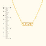 Gold necklace featuring a pendant that reads "LOVE," accompanied by a ruler for size reference.