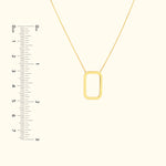Gold rectangular pendant necklace on a delicate chain, displayed with a ruler for size reference.