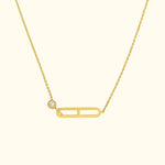 Gold necklace featuring a minimalistic safety pin design with a small diamond accent.