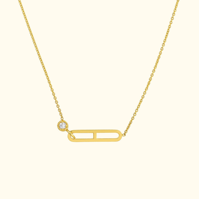 Gold necklace featuring a minimalistic safety pin design with a small diamond accent.