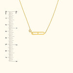 Gold necklace with a decorative safety pin charm and a small diamond accent.