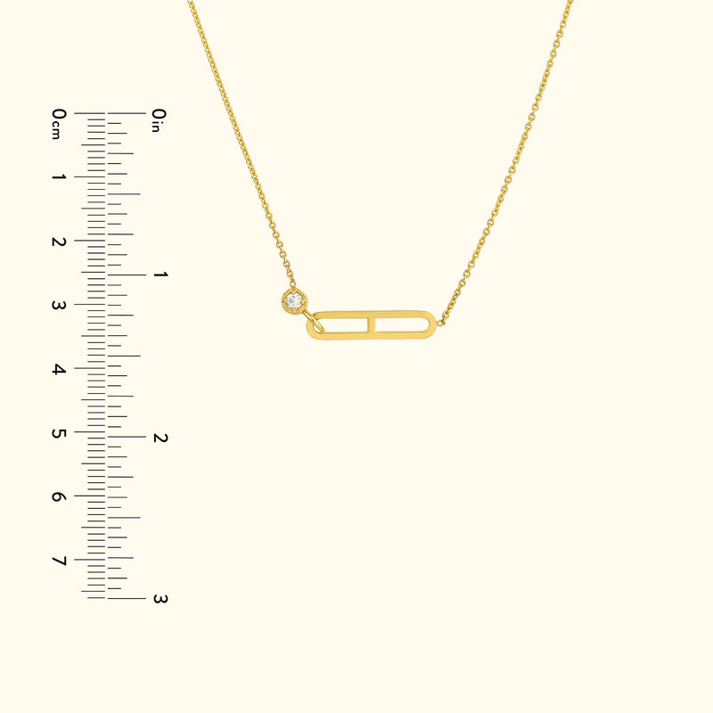 Gold necklace with a decorative safety pin charm and a small diamond accent.