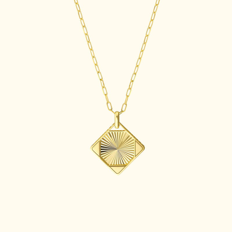 Faceted gold pendant on a delicate chain, featuring a sunburst design.