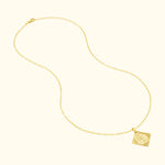 Delicate gold necklace with a square pendant featuring a sunburst design.