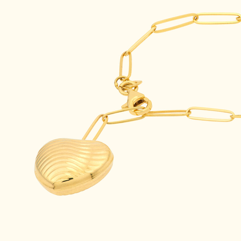 Gold necklace featuring a heart-shaped pendant with ribbed detailing.