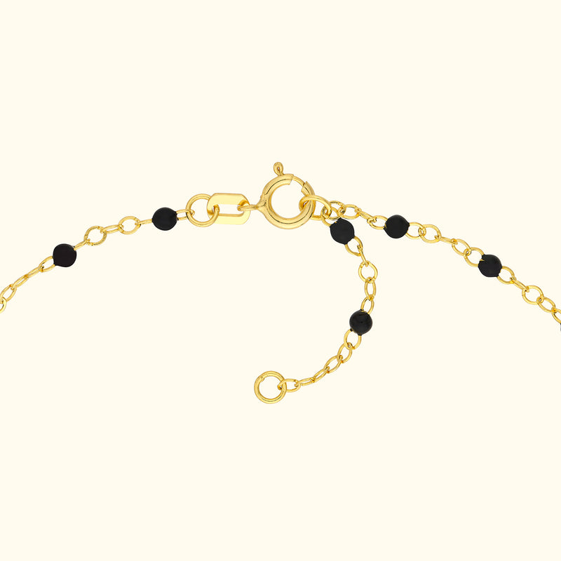 Gold chain bracelet with black beads and a secure clasp.