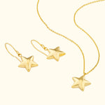Gold star-shaped earrings and matching necklace on a light background.