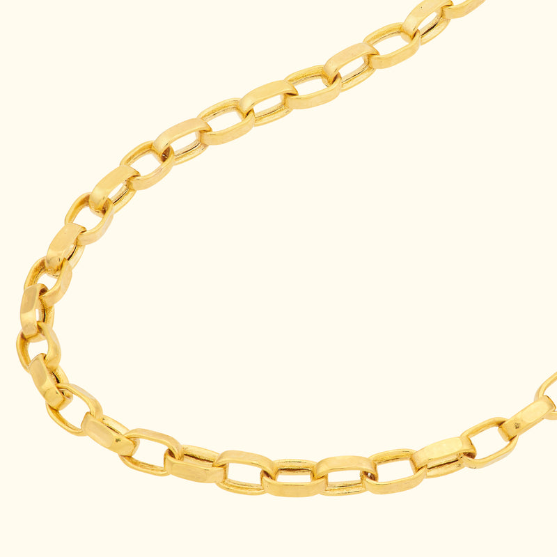 Gold link chain necklace on a light beige background.