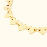 Gold heart-shaped link bracelet against a light background.