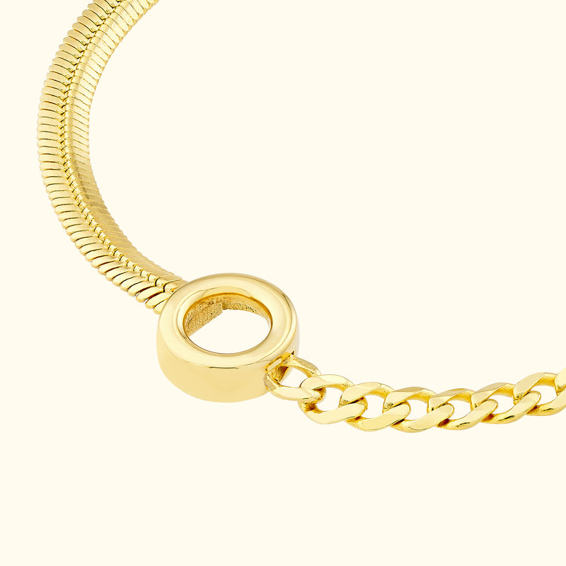Close-up of a gold bracelet featuring a smooth disc and interlinked chain.
