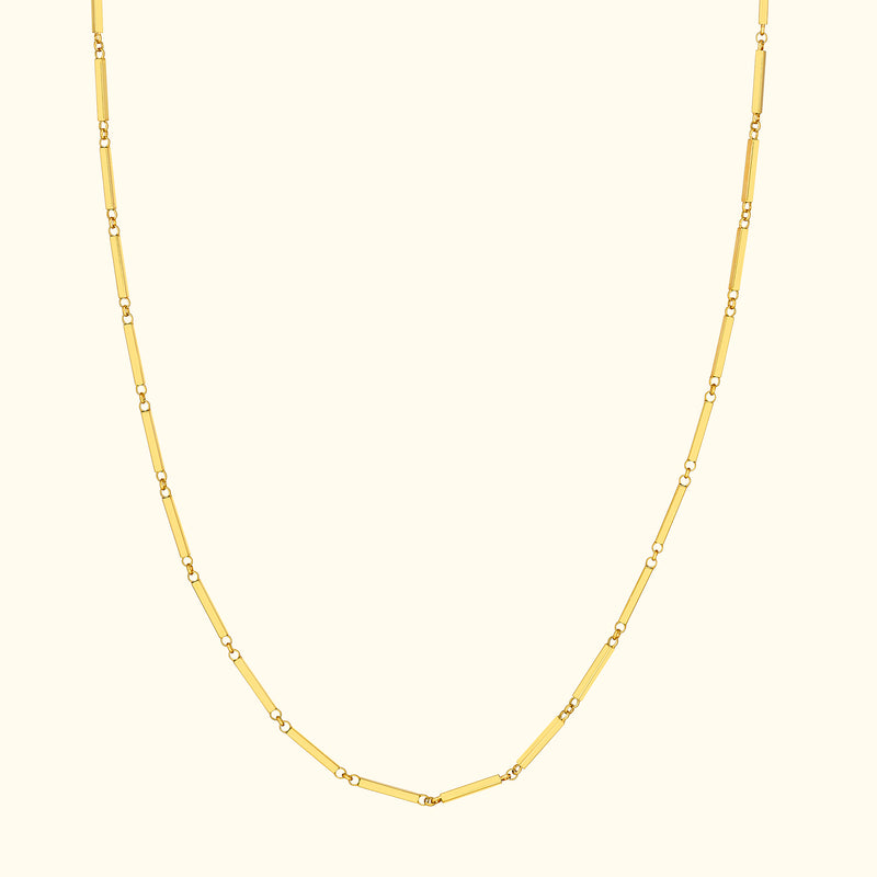 Yellow gold chain necklace with alternating link shapes on a light background.