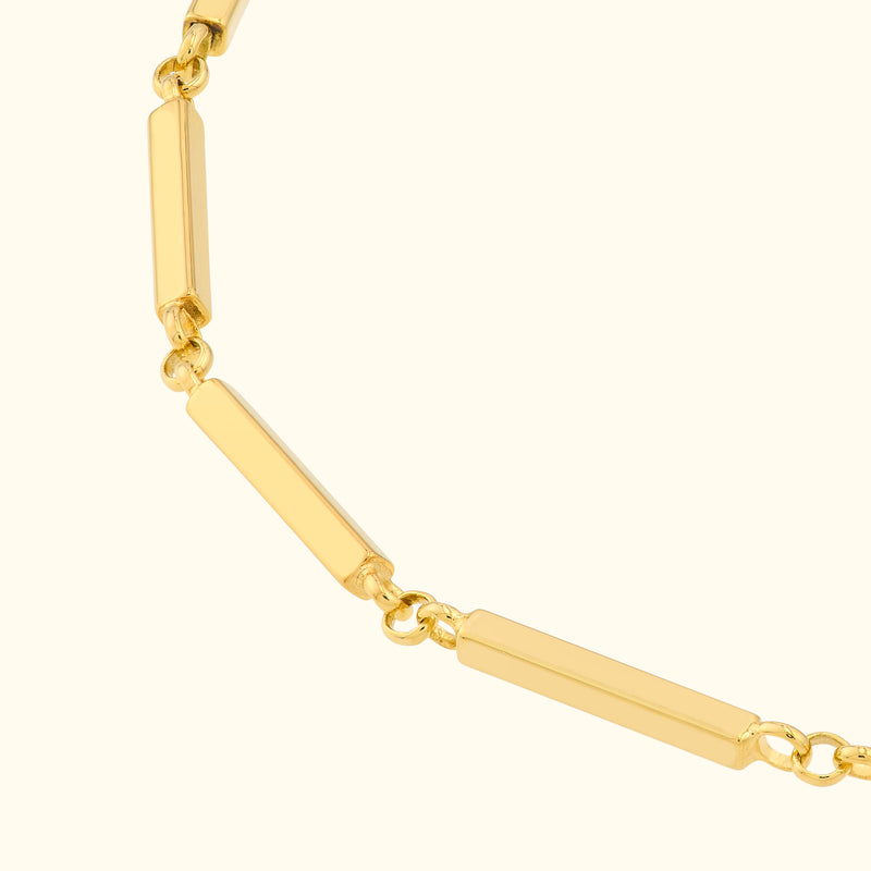 Gold bar link necklace with a smooth, shiny surface against a neutral background.