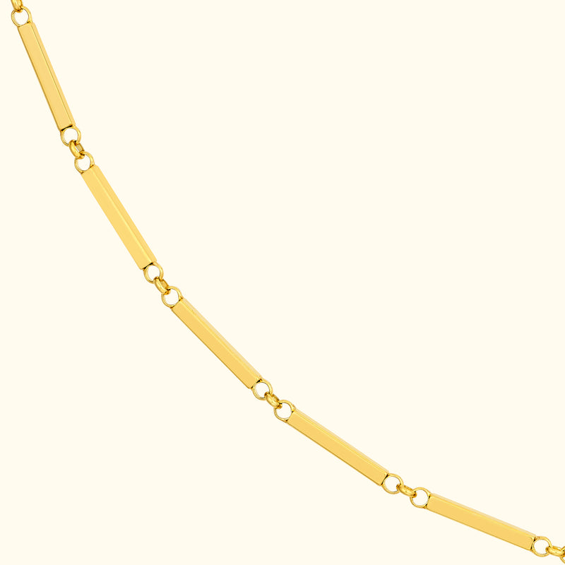 Gold necklace with elongated rectangular links on a light background.