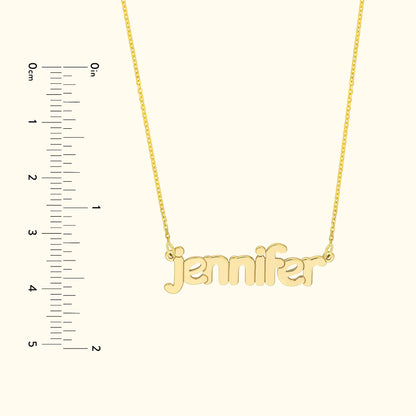 Gold name necklace with the text "jennifer," displayed next to a ruler for size reference.