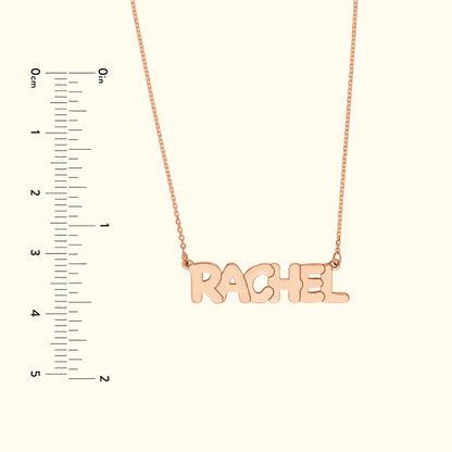 Rose gold necklace with the name "RACHEL" in bold, playful lettering.