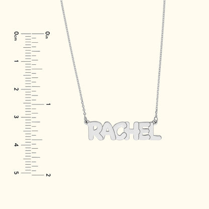 Silver necklace featuring the name "RACHEL," displayed with a ruler for size reference.