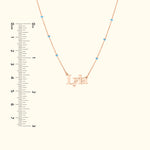 Rose gold necklace with the name "Lyla" and small turquoise beads, paired with a ruler for size reference.