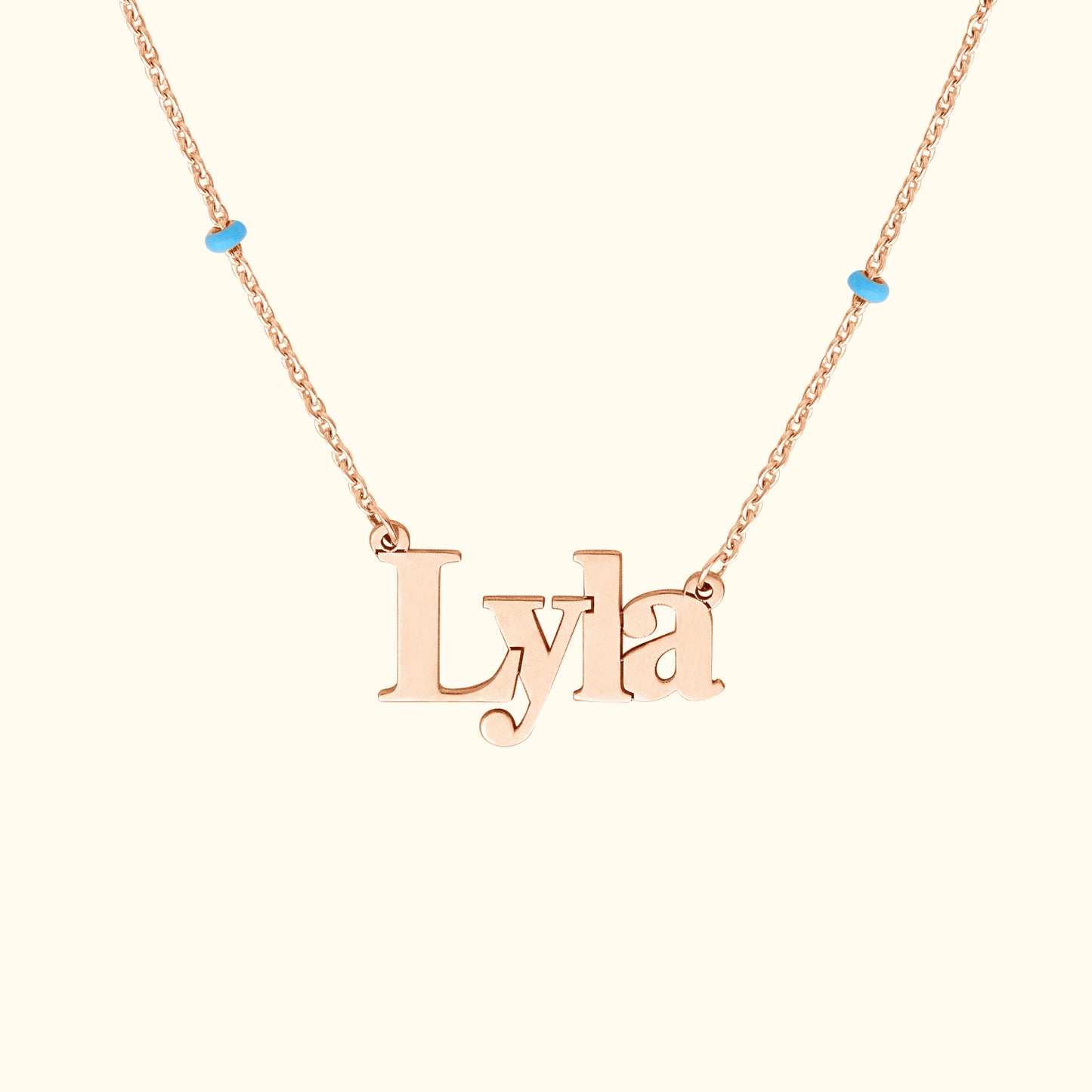 Rose gold name necklace featuring the name "Lyla" with blue accents.