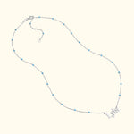 Silver necklace with light blue beads and a pendant spelling "Lyra."