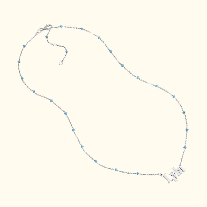 Silver necklace with light blue beads and a pendant spelling "Lyra."