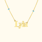 Gold necklace with the name "Lyla" and small turquoise beads on each side.