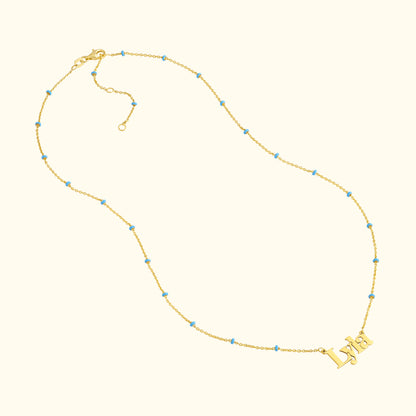 Gold necklace featuring the name "Lydia" with blue bead accents.